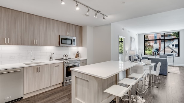 A modern kitchen with a central island, stainless steel appliances, and a large window offering a view of the outside. - Global Luxury Suites at Bethesda Metro (Bethesda)