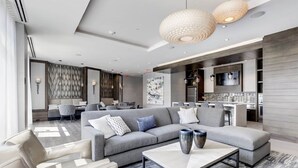 A modern living room with a grey sectional sofa, a coffee table, and pendant lighting. - Global Luxury Suites at Bethesda Metro (Bethesda)