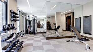 A modern gym with weightlifting equipment, cardio machines, and a mirror wall. - Global Luxury Suites at Bethesda Metro (Bethesda)
