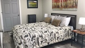 Une chambre à coucher avec un lit, une table de chevet, une lampe et une porte.