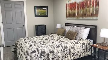 Une chambre à coucher avec un lit, une table de chevet, une lampe et une porte.