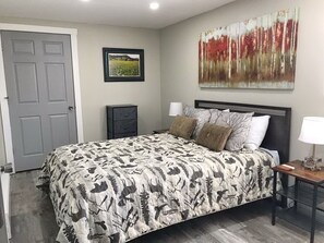A bedroom with a bed, a nightstand, a lamp, and a door. - Great Location, Spectacular Mountain Views and gas firepit! #3306 (Estes Park)