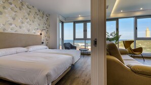 A modern hotel room with a large bed, a sofa, and a balcony with a view of a tower. - TH Apartments by Como en Casa (A Coruña)