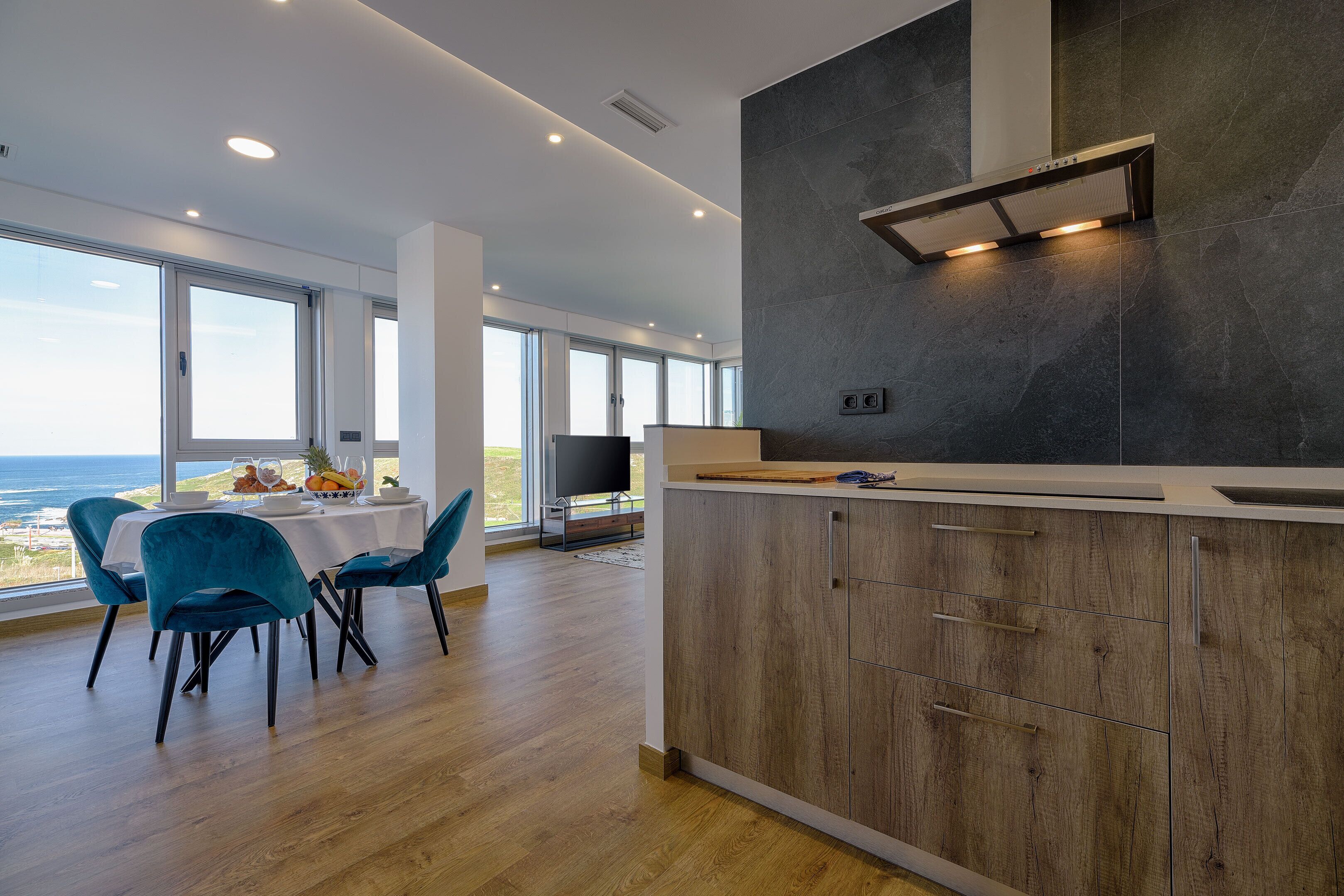 Una cocina moderna con una isla grande, armarios de madera y vista al océano.