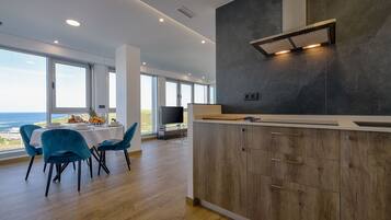 Una cocina moderna con una isla grande, armarios de madera y vista al océano.