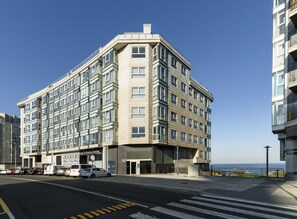A multi-story hotel with a modern design, featuring a prominent entrance and a view of the sea. - TH Apartments by Como en Casa (A Coruña)