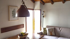 A cozy room with a wooden ceiling, a wooden table with a fruit bowl, a sofa with patterned cushions, and a framed botanical print on the wall. - Cosy flat for nature lovers and peace seekers in the mountain village of Livo (Livo)