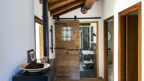 A hallway with a rustic wooden wall, a black pipe, and a plate with pinecones on a blue cabinet. - Cosy flat for nature lovers and peace seekers in the mountain village of Livo (Livo)
