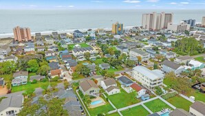 Zona residencial con casas, piscina y playa al fondo.