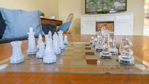Un tablero de ajedrez con piezas sobre una mesa de vidrio en una habitación con una televisión y un sofá.