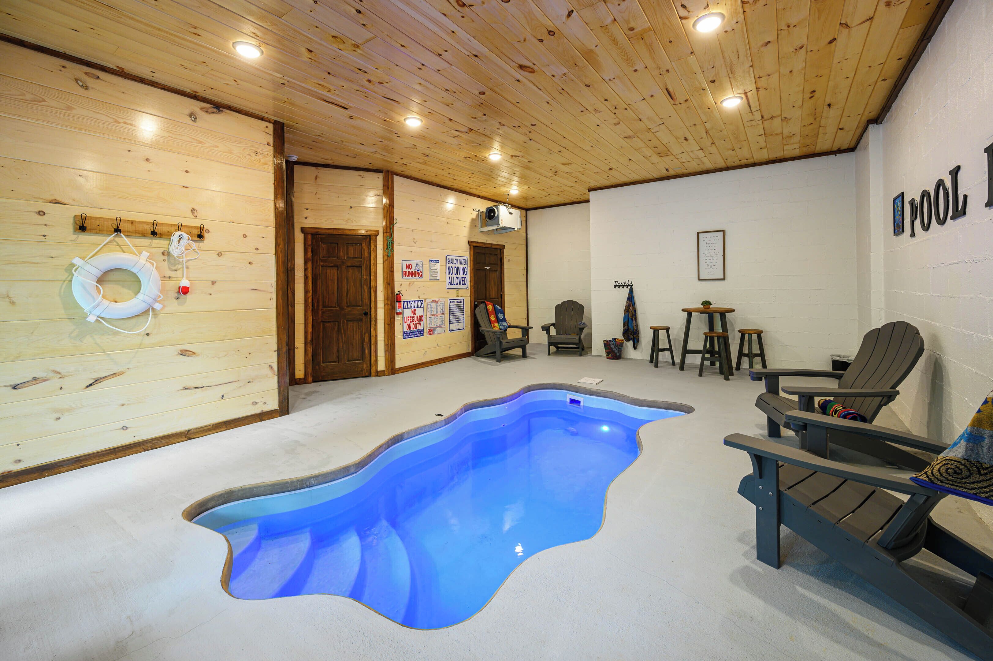 A room with a blue pool, wooden walls, and Adirondack chairs.