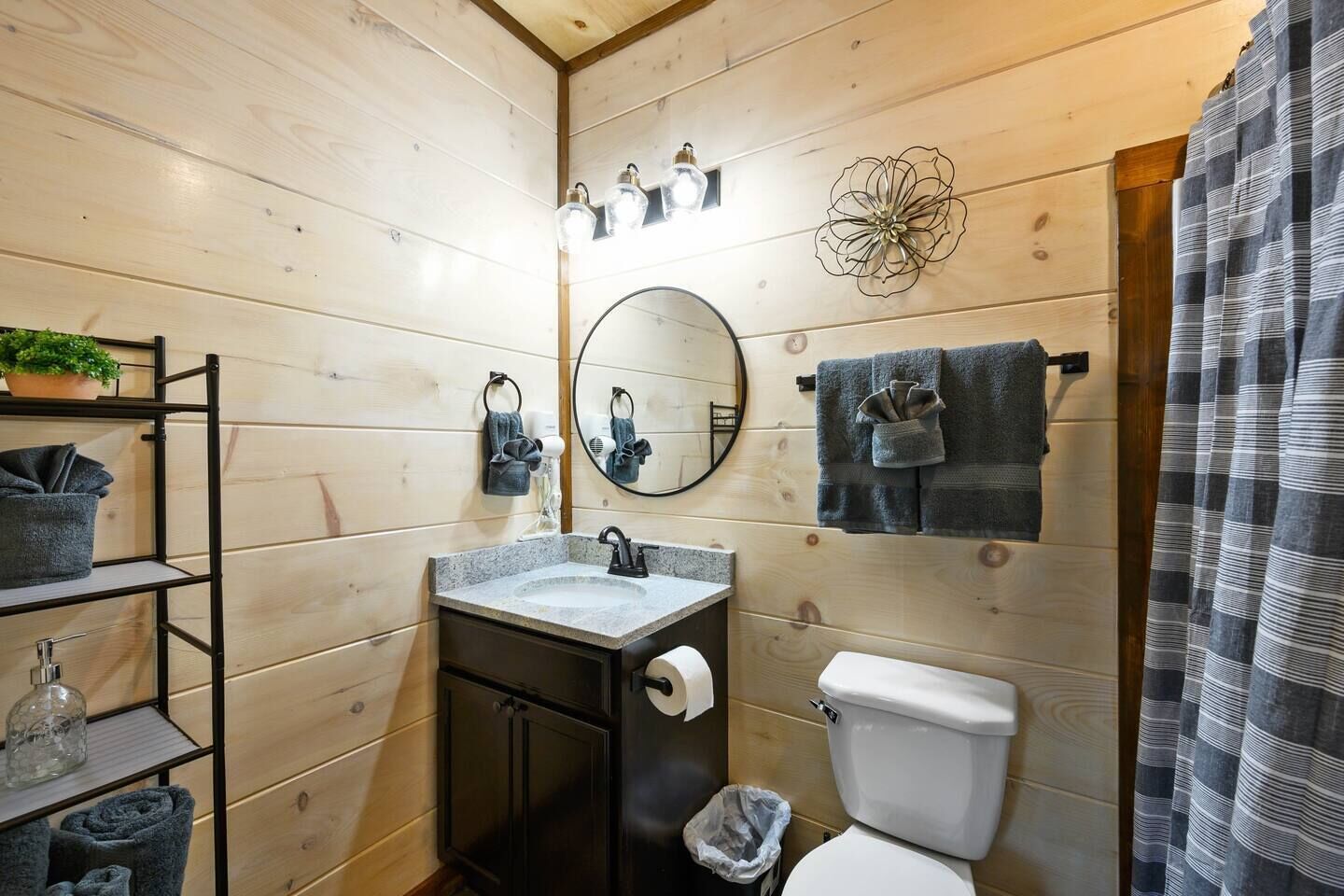 A compact bathroom with a wooden interior, a sink with a mirror, a toilet, and a shower curtain.
