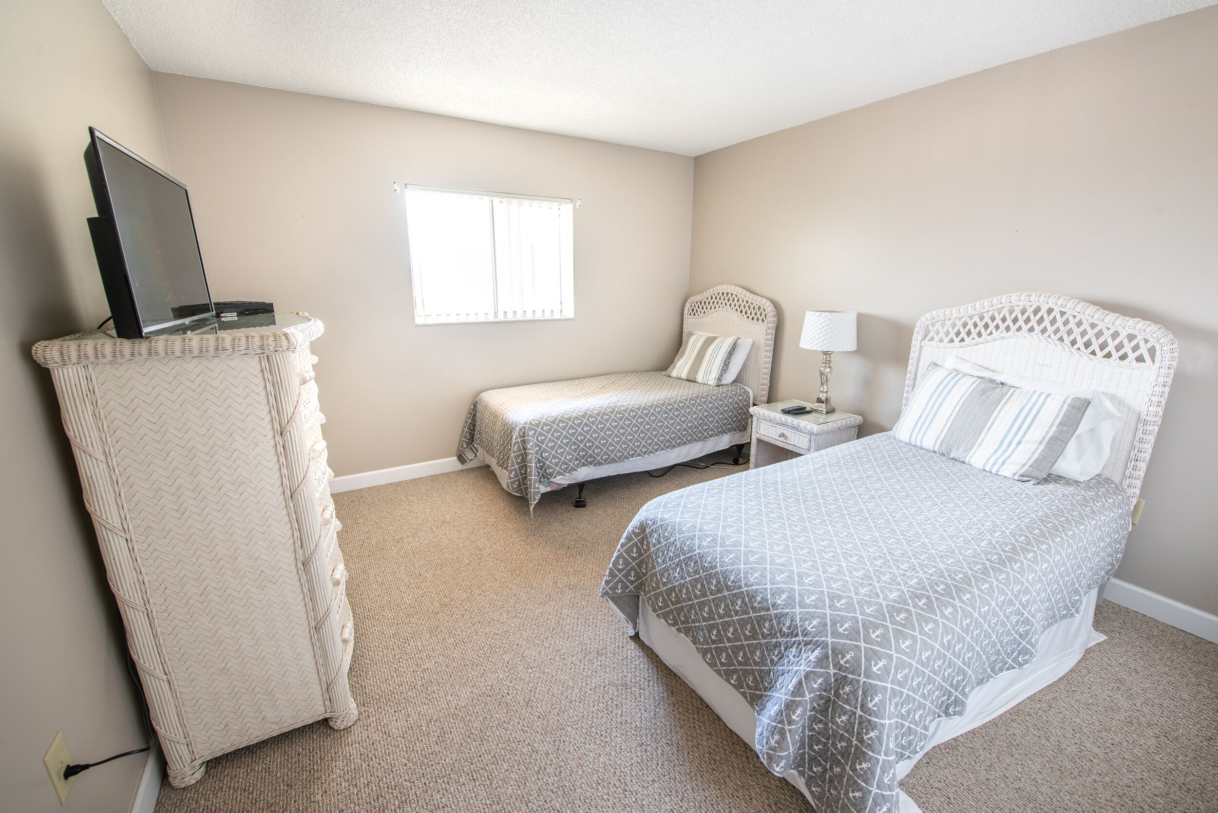 A bedroom with a bed, two bedside tables, a TV on a stand, and a window.