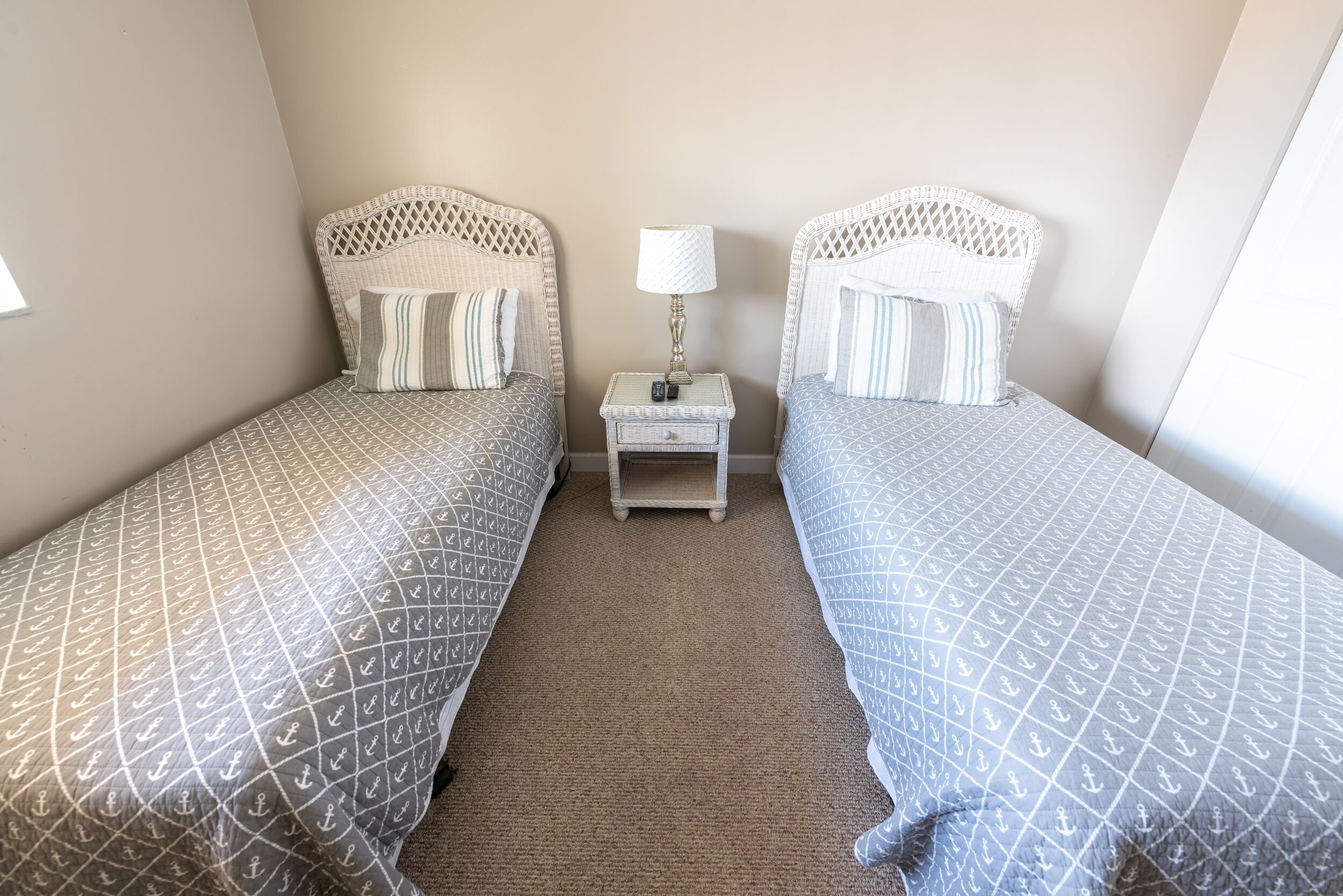 A twin bedroom with two beds, each with a patterned bedspread, a nightstand with a lamp, and a small drawer.