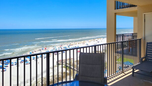A balcony with a view of a beach with umbrellas and people. - Best Splash Pad in town 2/2 sleeps 8 Phoenix V813 (Orange Beach)