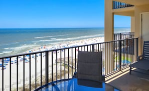Uma varanda com vista para uma praia com guarda-sóis e pessoas.