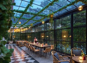 A greenhouse-style dining area with tables and chairs, surrounded by glass walls and a checkered floor. - Hyatt Centric Sector 17 Chandigarh (Chandigarh)