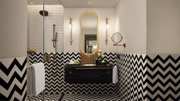 Un baño moderno con un patrón geométrico blanco y negro en forma de chevron, un espejo grande y una lámpara redonda empotrada en la pared.