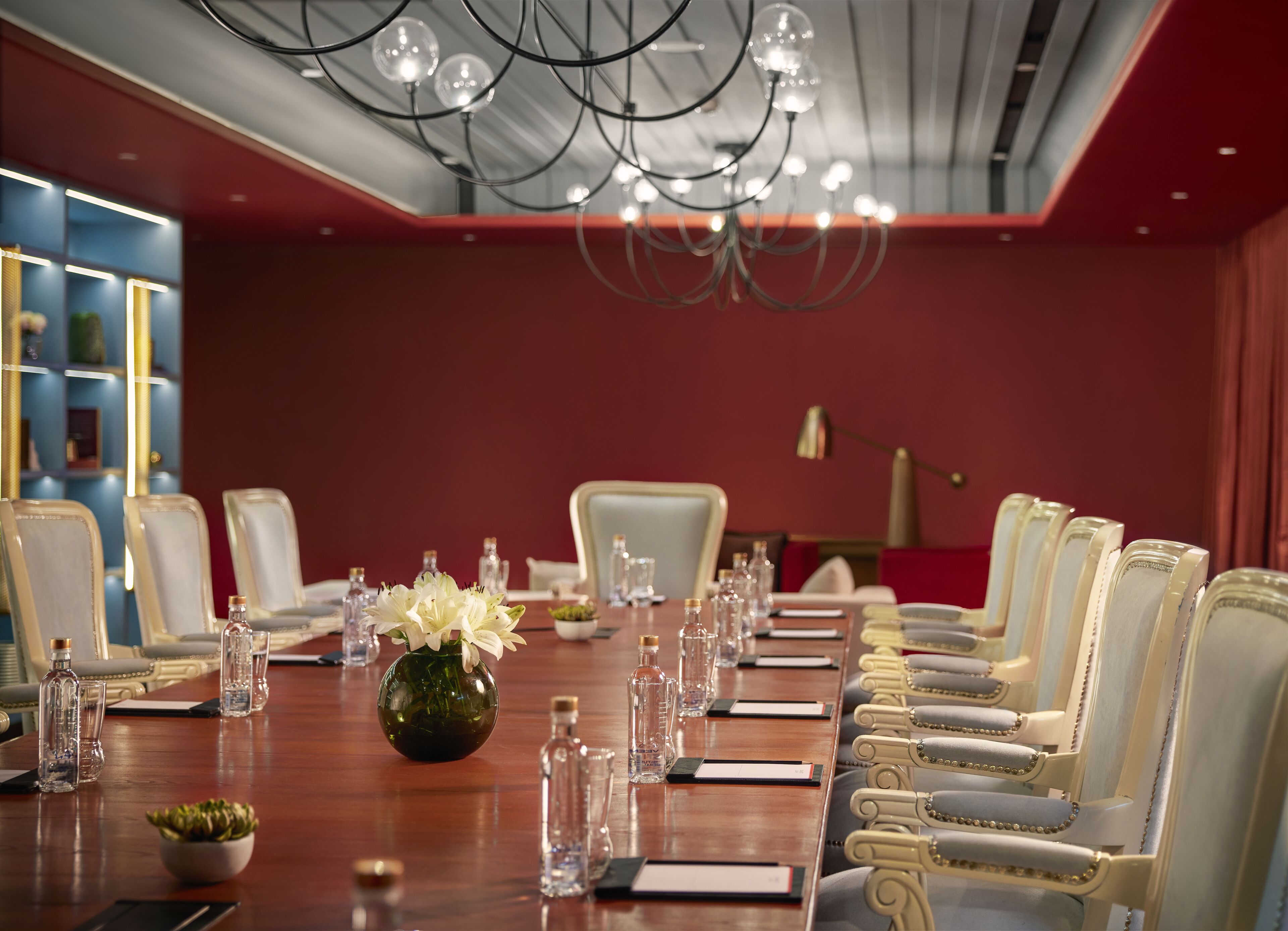Une salle de conférence avec une longue table, des chaises et un lustre.
