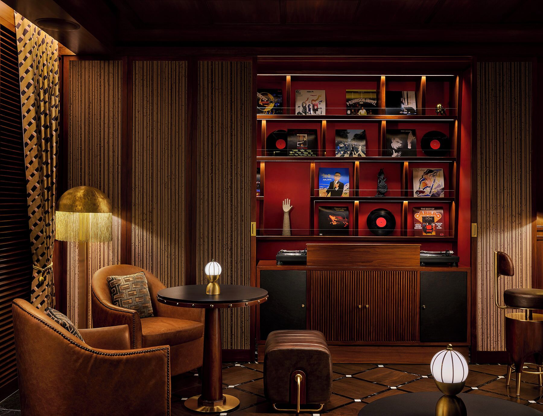 A cozy room with a wooden wall, a record shelf, a round table, and a comfortable chair.