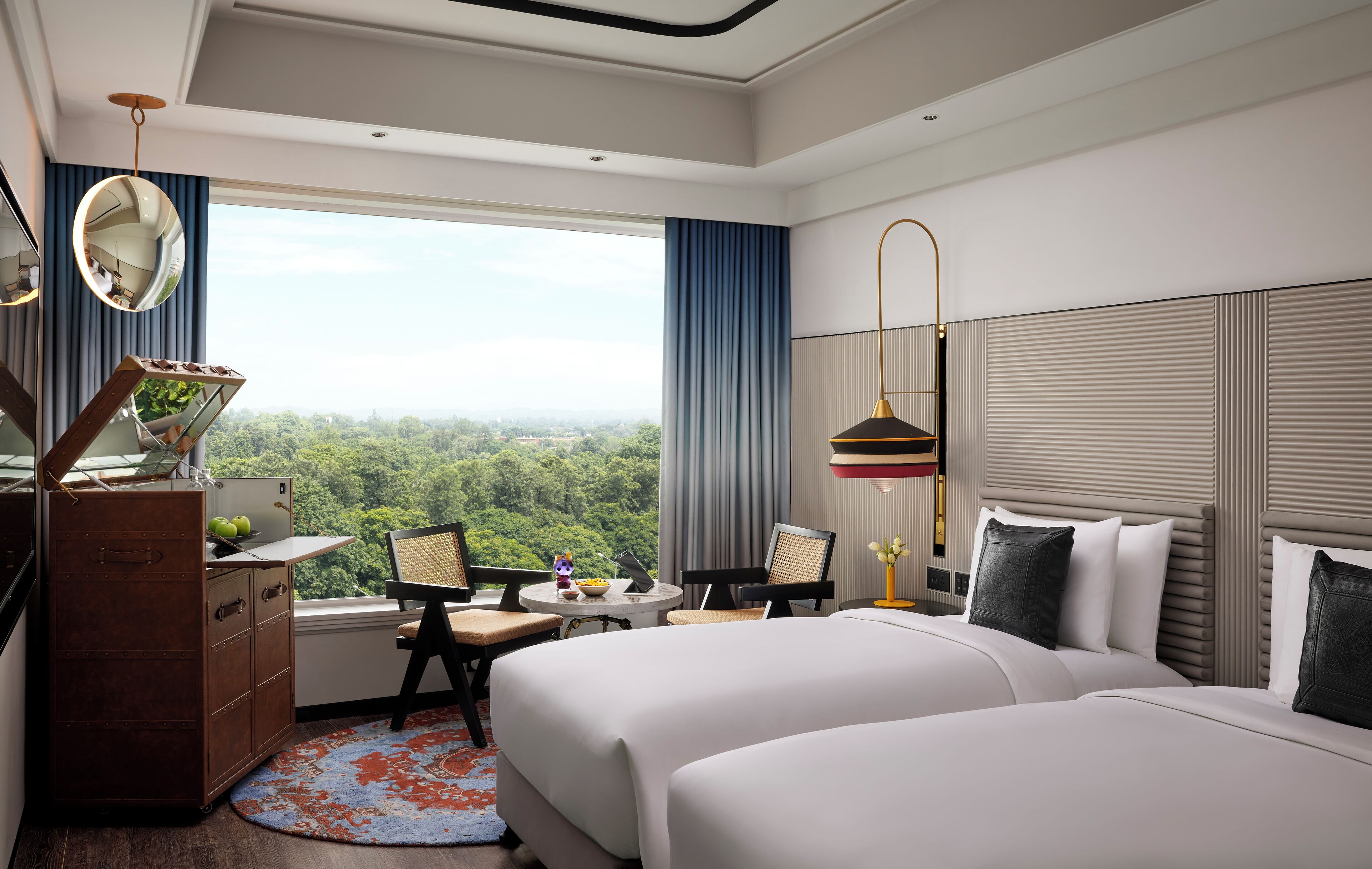 A modern hotel room with a large bed, a desk, and a view of the forest.