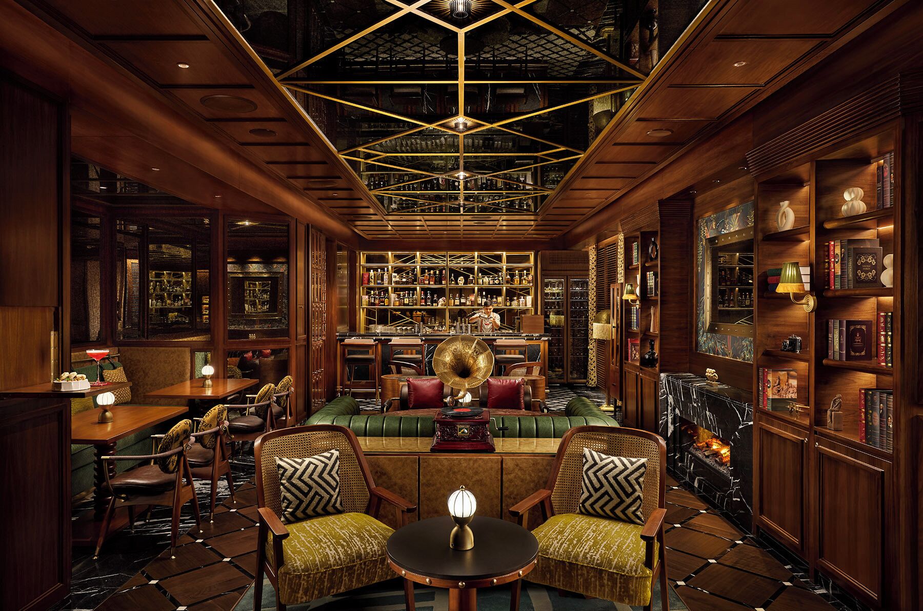 A bar area with wooden furnishings, a central seating area with a record player, and a bookshelf filled with books and bottles.