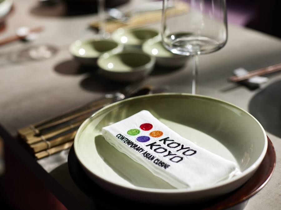 A table setting with a green bowl, chopsticks, and a napkin with the text "KOYO CONTEMPORARY ASIAN CUISINE".