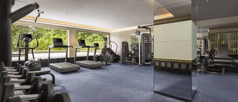 A modern gym with cardio machines, weightlifting equipment, and a large mirror.
