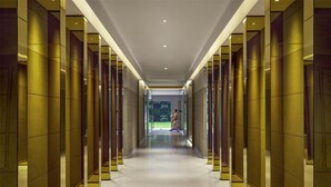 A modern hallway with reflective walls and a polished floor, leading to a glass door. - Hyatt Centric Sector 17 Chandigarh (Chandigarh)