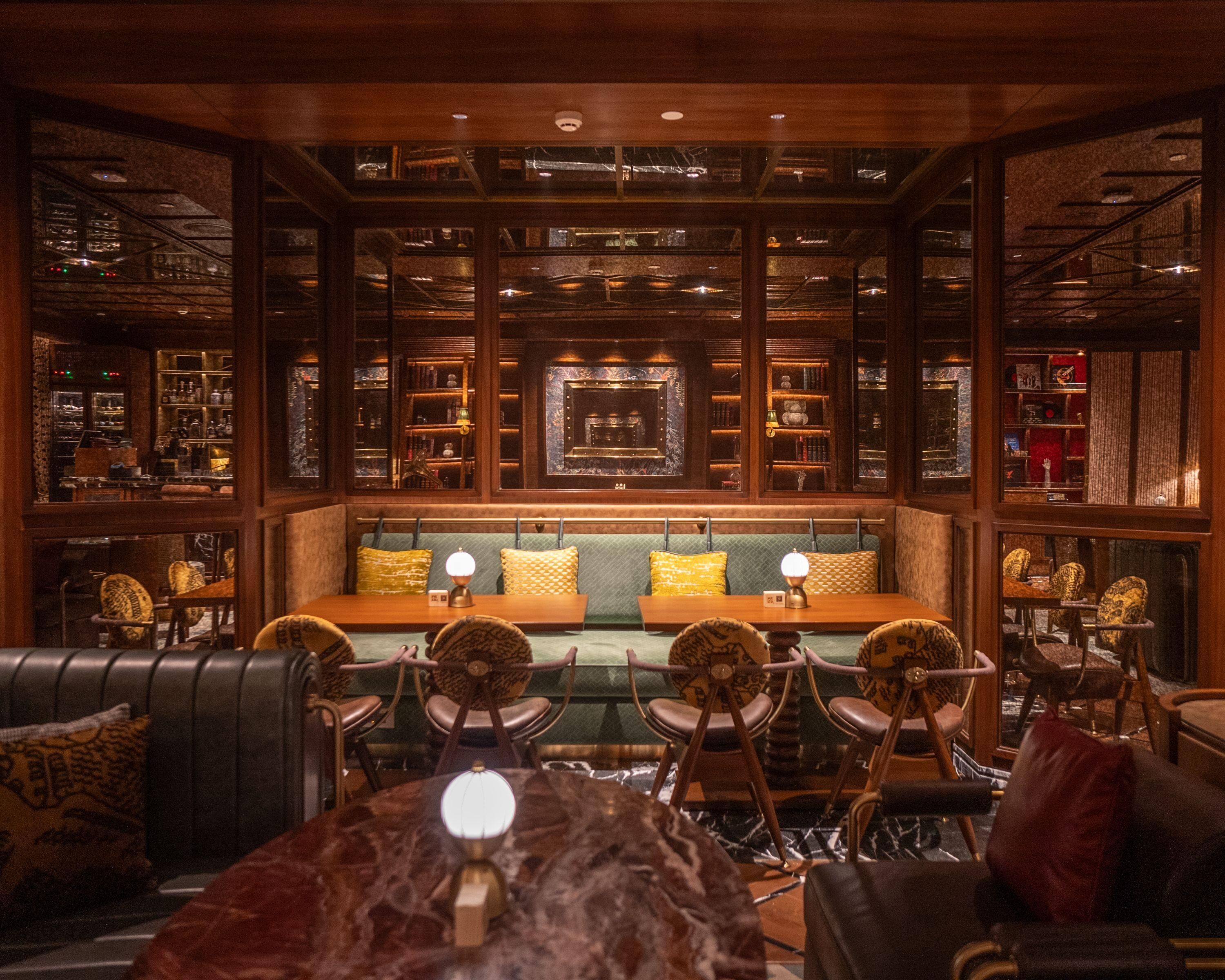A cozy library-style seating area with bookshelves, a central bench, and a marble table with chairs.