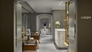 Een moderne hotelgang met een centrale doorgang, zitgedeeltes en een receptiebalie.