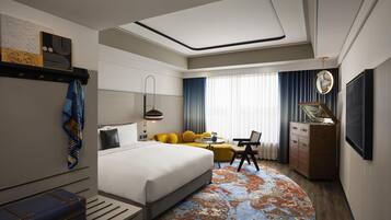 Quarto de hotel moderno com uma cama grande, um sofá, uma escrivaninha e um aparador.