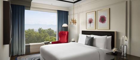 Una habitación de hotel moderna con una cama grande, una silla roja, una mesita de noche y vistas al exterior.