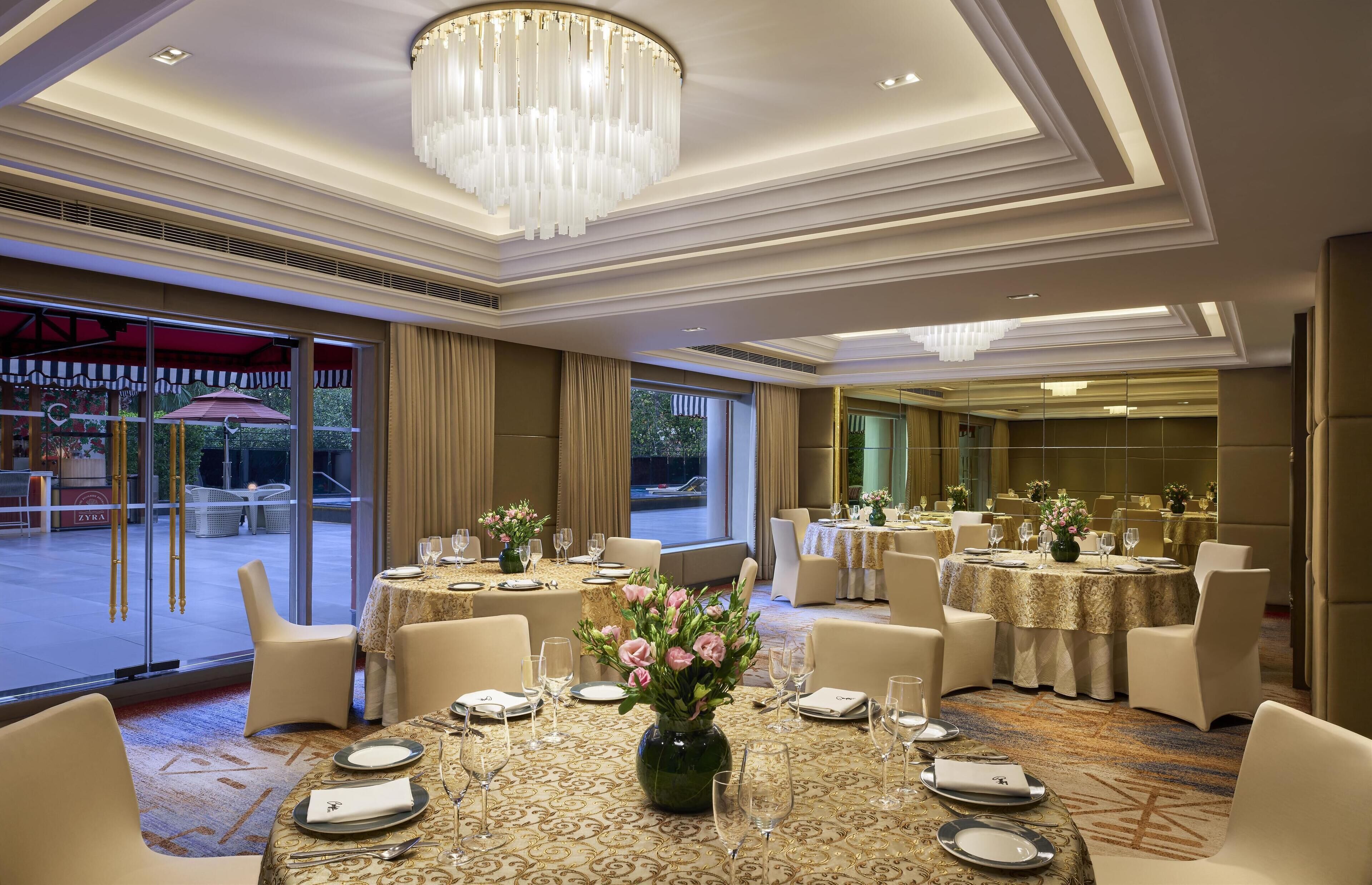 Un comedor de hotel con mesas redondas, sillas y un candelabro.