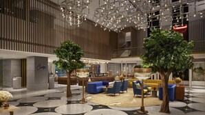 Een moderne lobby met een centrale zithoek, een trap en een receptiebalie.