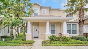 A two-story residential building with a beige facade, white columns, and a covered front porch. - EV_1447 - 3 Bed, 3 Bath Townhome with Screened-In Private Pool and Access Resort (clermont)