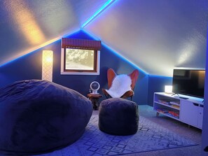 A room with a sloped ceiling, a window, a television, and bean bags. - The Overlook Nook l Great View l King Bed l Fenced Yard (Spokane)
