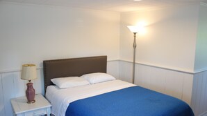 Un letto rifatto con una coperta blu, una lampada da comodino e un piccolo tavolino.
