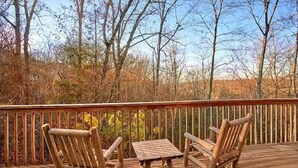 Eine Holzterrasse mit zwei Schaukelstühlen und einem kleinen Tisch.