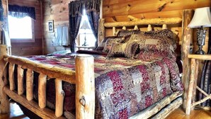 Ein Zimmer in einer Holzhütte mit einem Bett, einer Lampe und einem Fenster mit Vorhängen.