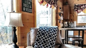 Ein gemütliches Blockhaus-Interieur mit Ledersessel, Lampe und einem 'Welcome'-Schild.