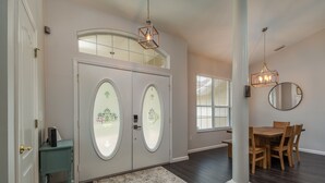A spacious entryway with a double door featuring decorative glass panels, a wooden dining table with chairs, and a chandelier. - HEATED PRIVATE POOL | CLOSE TO RAINBOW RIVER, CRYSTAL RIVER & GOLFING (Citrus Springs)