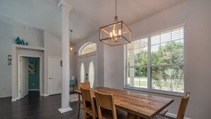 A dining area with a wooden table and chairs, a hanging light fixture, and a window with blinds. - HEATED PRIVATE POOL | CLOSE TO RAINBOW RIVER, CRYSTAL RIVER & GOLFING (Citrus Springs)