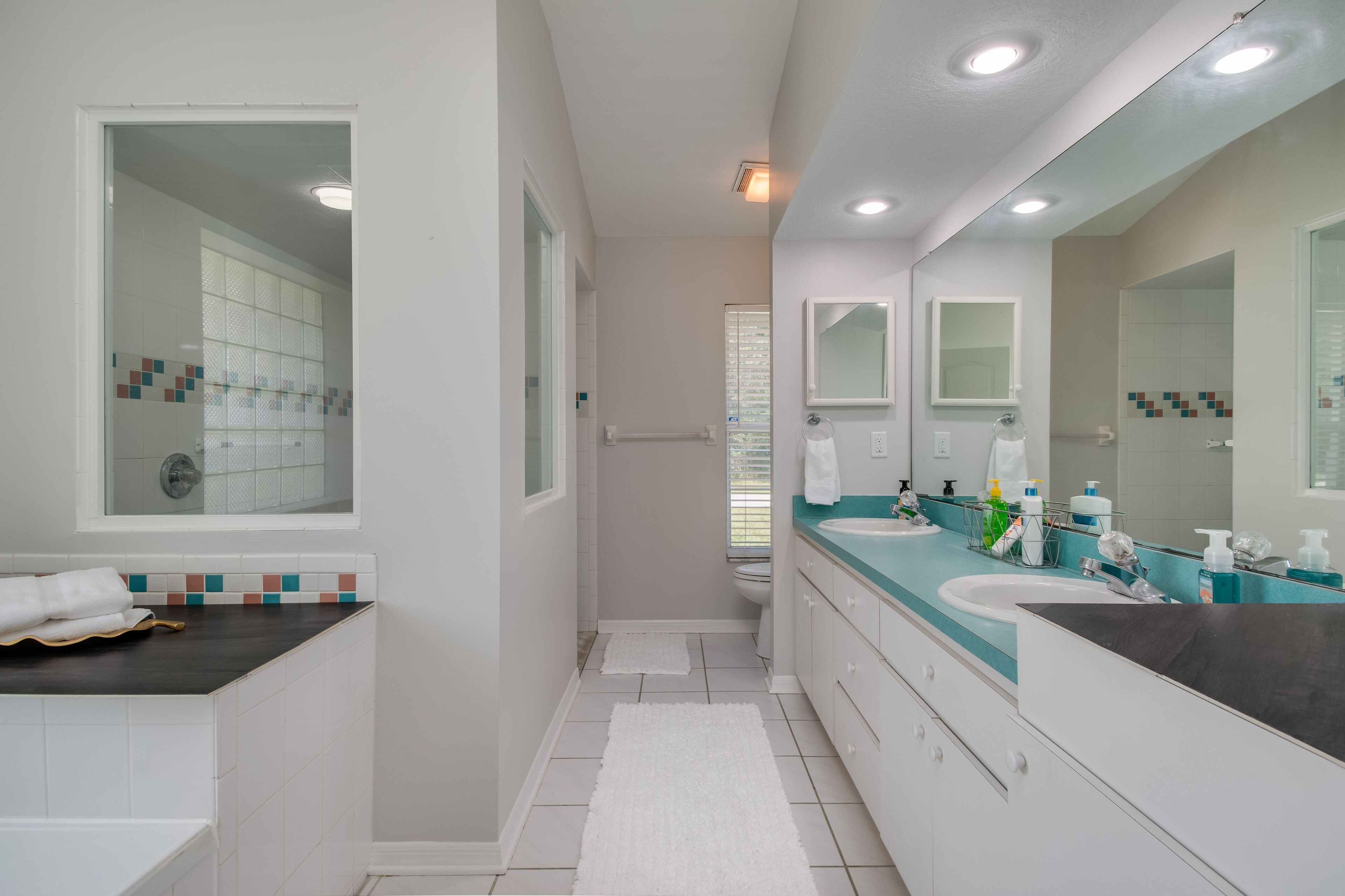 Un baño moderno con un espejo grande, dos lavamanos y una zona de ducha.