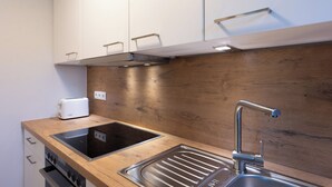 Una cocina moderna con encimera de madera, estufa integrada, lavamanos y armarios blancos.