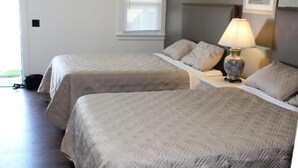 Deux lits simples avec des têtes de lit et des pieds de lit assortis, une table de chevet avec une lampe et une fenêtre avec des stores.
