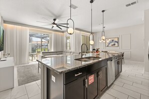 A modern kitchen with a central island, stainless steel appliances, and pendant lighting.