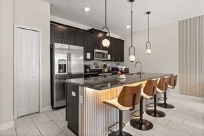 A modern kitchen with a central island, stainless steel appliances, and bar stools.