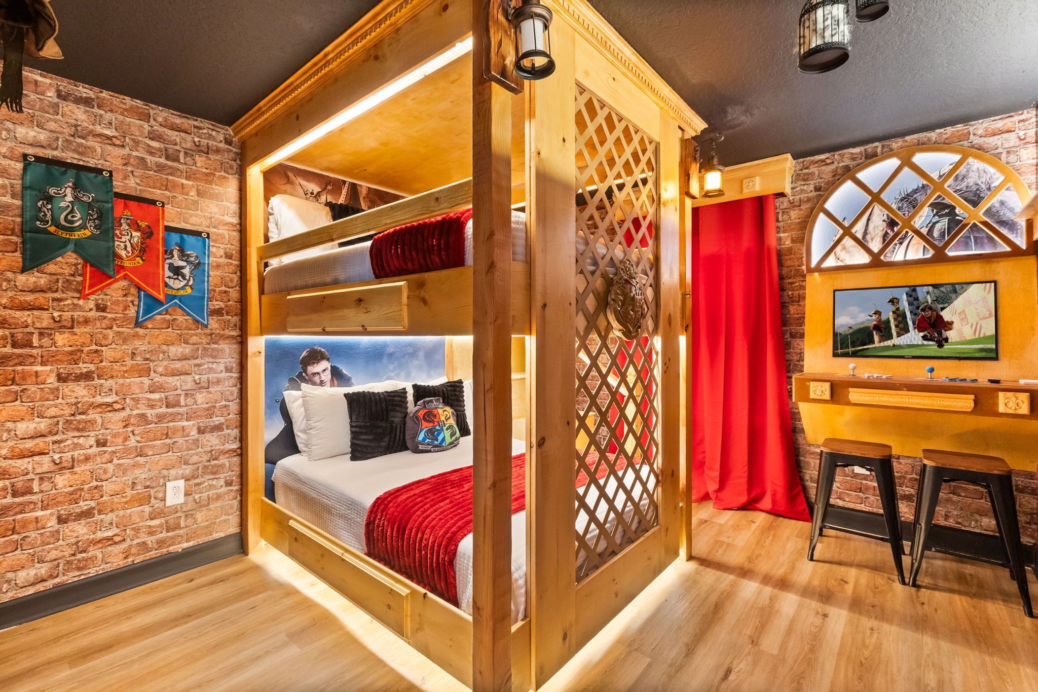 A room with a bunk bed, a television, and a brick wall.