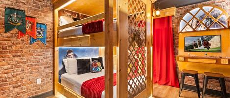 A room with a bunk bed, a television, and a brick wall.
